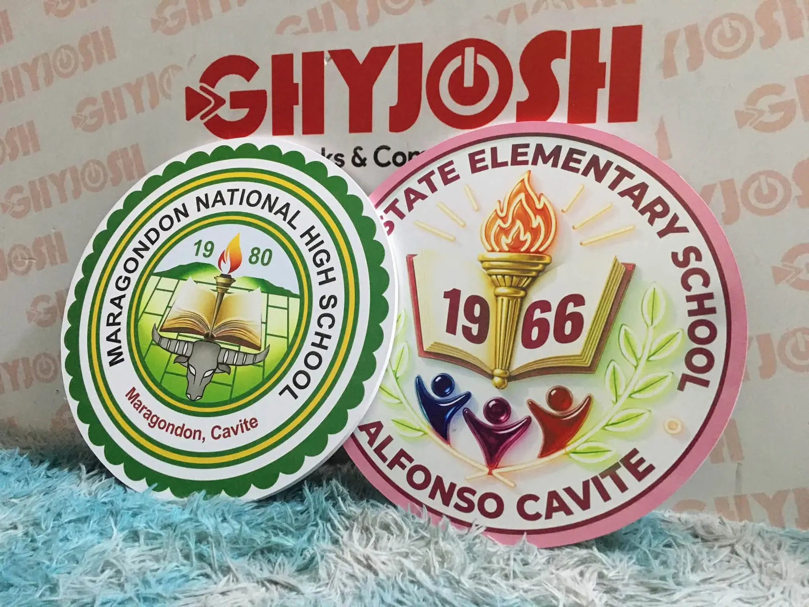 Two round school seals, one green and one pink, in front of the shop mark